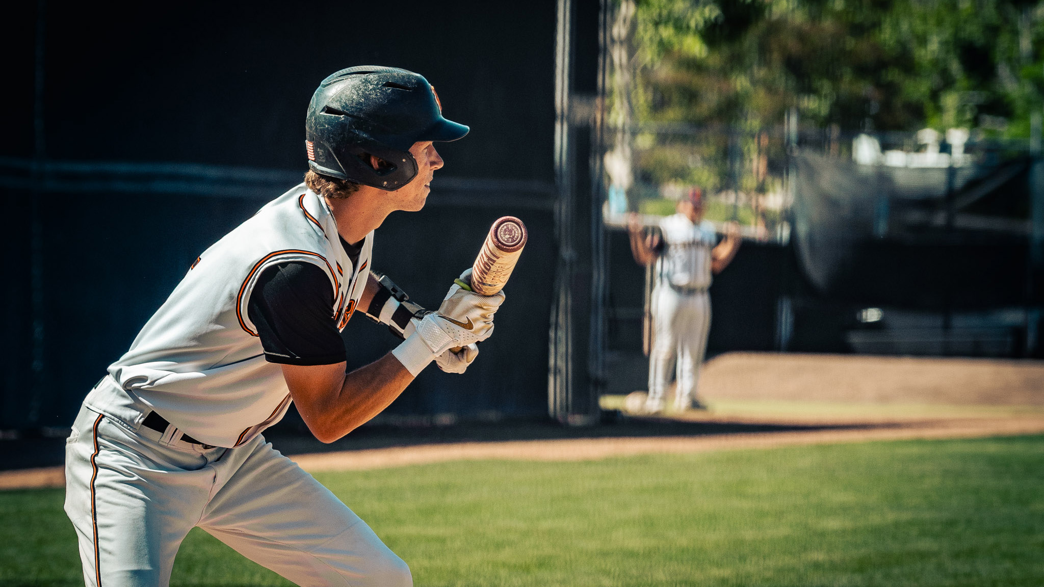 Baseball player in a white uniform gets ready to bunt