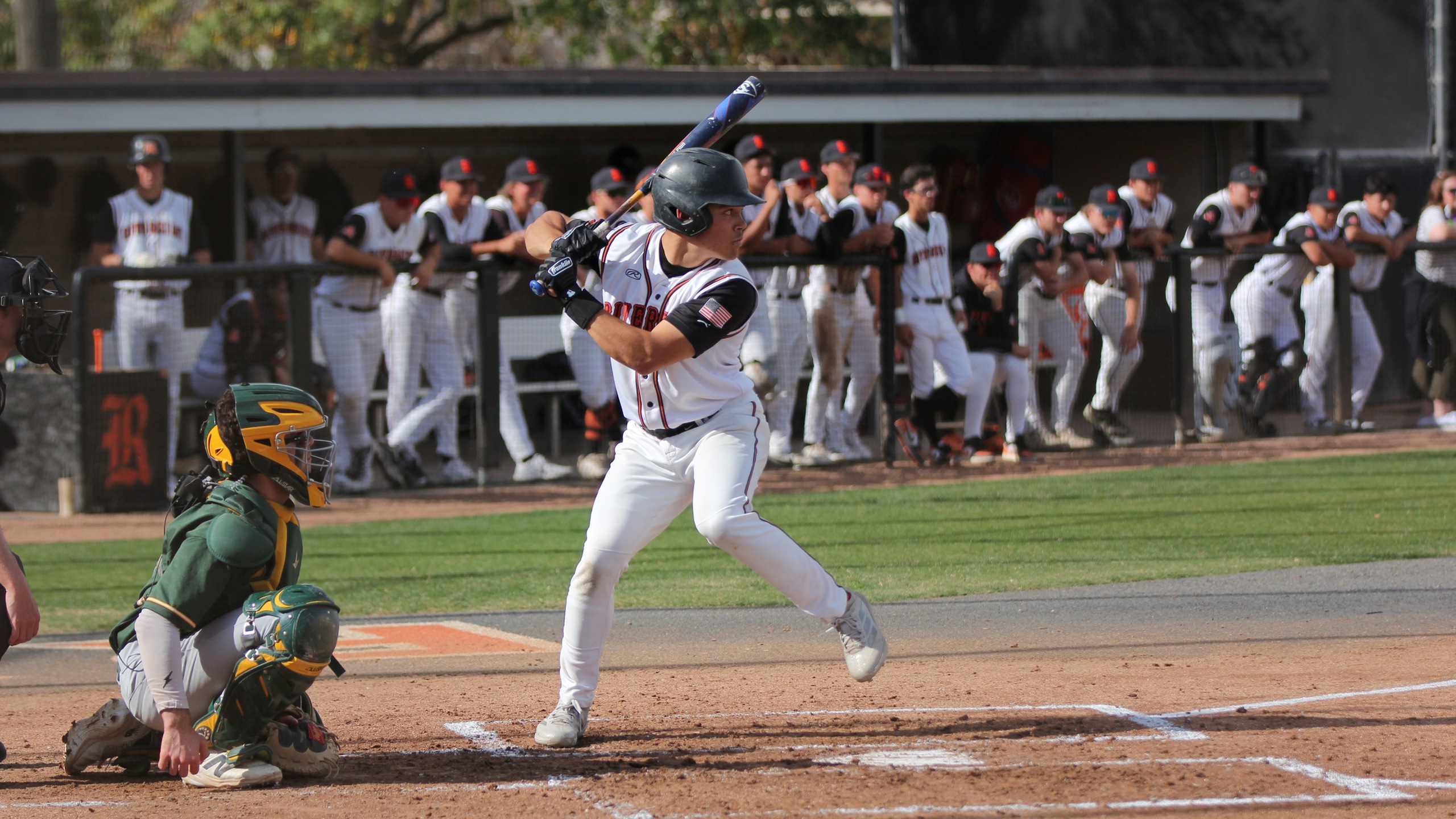 Baseball player in white uniform gets ready to swing the bat