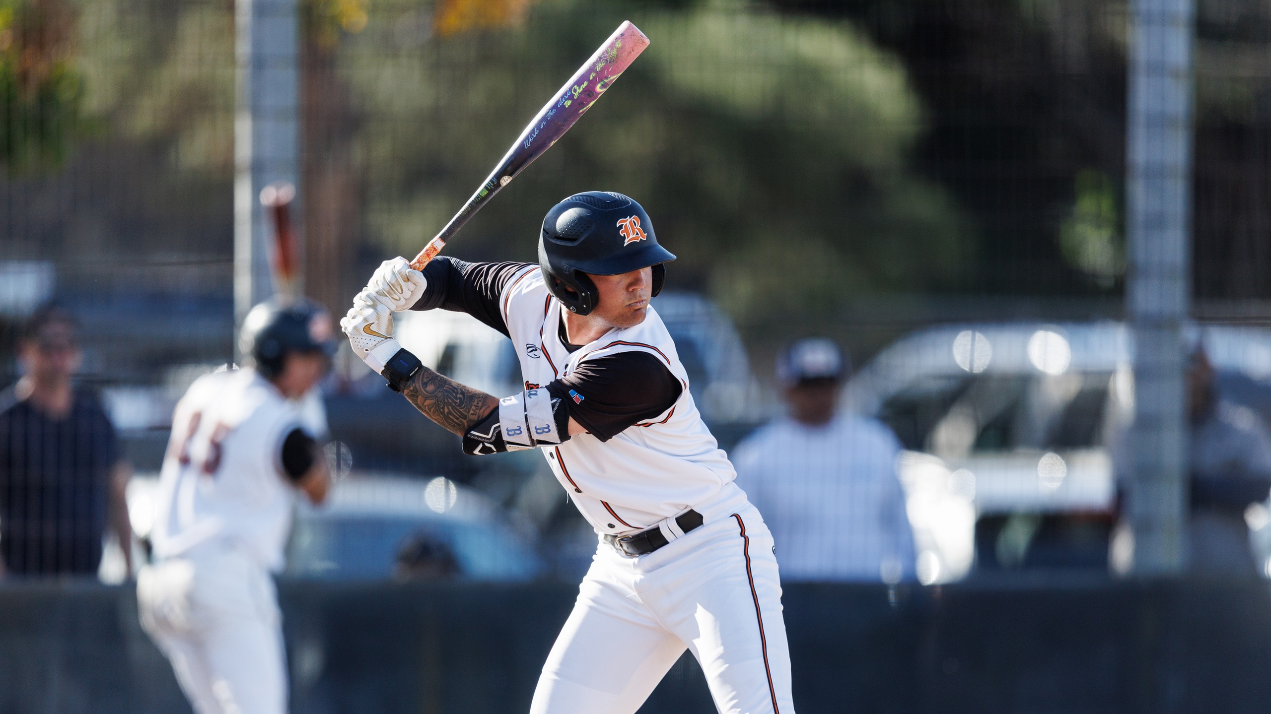 Baseball player in white uniform gets ready to swing the bat.