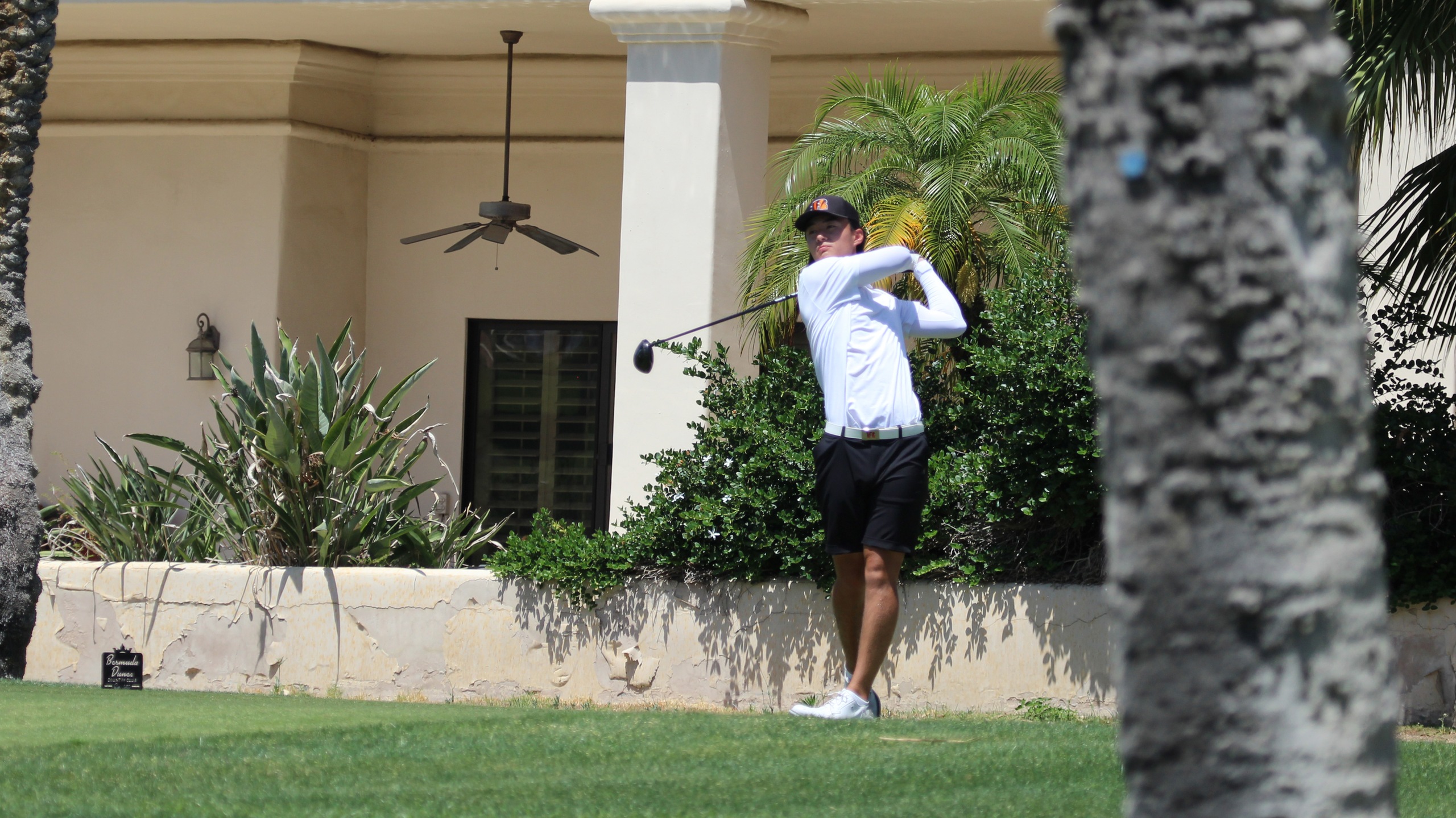 Golfer in a white shirt swings a golf club