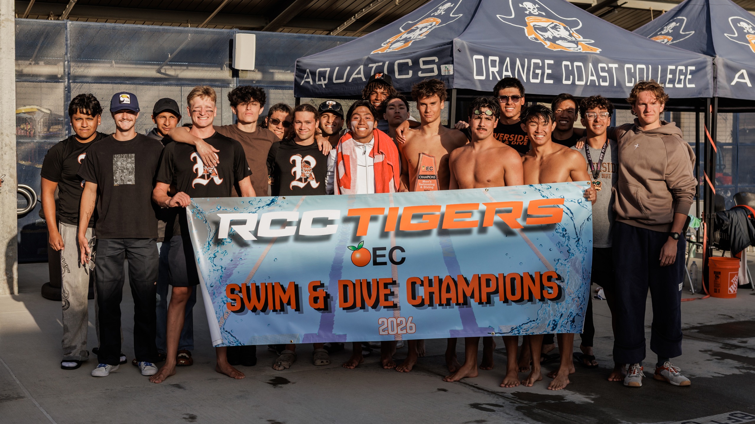 RCC men's swim and dive team poses with a banner that says 